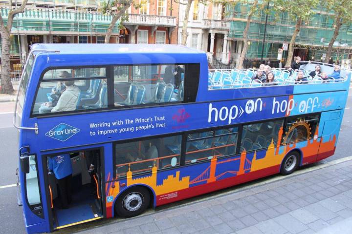 a blue double decker bus driving down a street